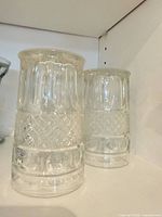 Two of the pressed-glass tumblers showing pattern details and height