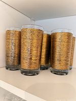 Six of the eight gold-wrapped glasses on shelf