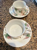 Two teacups each on matching saucer, showing overall design and condition