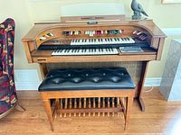 Front view of organ with bench showing keyboards, stop tabs, pedalboard