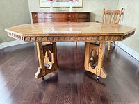 Full view of table showing top, apron carving, pedestal base, caster wheels