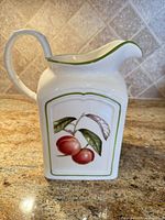 Front view showing fruit motif, handle, green rim