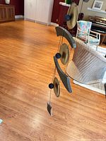 Full length view of wind chime hanging freely showing discs, grey bars, beads, and cord