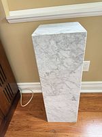 Full front view of faux marble pedestal showing overall shape and finish