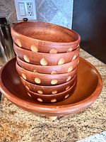 Stacked view of six small bowls with dotted inlay inside large serving bowl