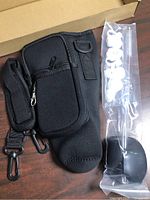 Neoprene sleeve with attached strap clips beside sealed accessory pack