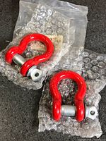 Two red bow shackles with silver pins in bubble wrap