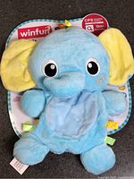 Front view of blue elephant comforter toy on card