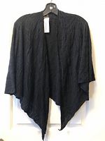 Front view of black textured shawl cape on hanger