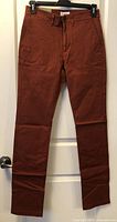 Front view of rust red slim chino pants hanging