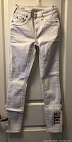 Front view of white True Religion Jennie Curvy skinny jeans showing overall design and vertical TRUE logo.