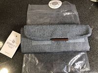 Folded carry case on top of original plastic sleeve with hang tag visible