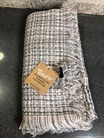 Folded Just Cozy plaid blanket scarf with retail hang tag