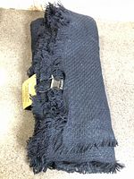 Rolled dark navy blanket scarf showing woven texture and fringe