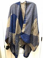 Front view of blue and beige striped poncho scarf hanging