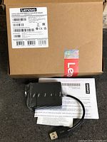 Closed Lenovo box with product label, adapter, cable and papers displayed