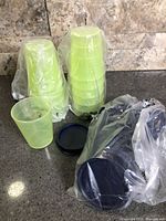 Stacks of neon yellow-green 2-oz Tupperware Midgets containers in plastic sleeves with loose navy lids