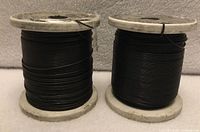 Two spools of black tie-wire on white plastic reels
