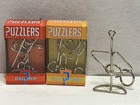 Group shot showing two boxed Puzzlers puzzles and one unboxed wire puzzle