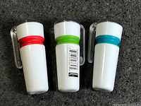 Three flashlights showing white bodies and colored accent rings