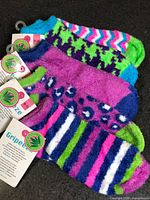 Stack of five Grippeeze fuzzy sock pairs showing patterns and tags