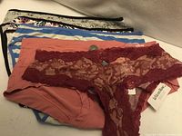 Stack of five assorted La Vie en Rose panties showing colours, lace, attached tags