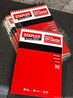 Stack of red Staples Business Depot top-bound notepads in plastic wrap