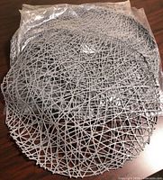 Stack of grey vinyl round placemats, some in plastic bag