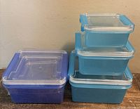 Four visible square containers, three blue stacked, one purple, showing clear snap lids
