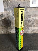 Front view of sealed Tenzi tube showing brand name and stacked dice