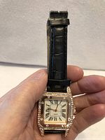 Front view of square rhinestone watch on black strap