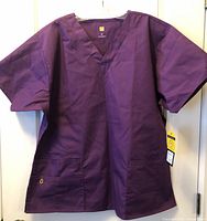 Front view of purple WonderWink scrub top showing V-neck, sleeves, and pockets