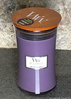 Front view of purple WoodWick jar candle with wood lid