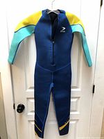 Front view of blue ZCCO youth wetsuit hanging on door