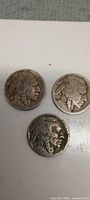 Three Buffalo nickels obverse on top, one obverse on bottom showing heavy wear