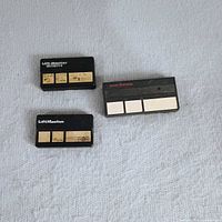 Front view of three remote transmitters showing brands, button counts, wear