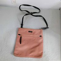 Front view of pink Kate Spade crossbody bag showing strap and pocket