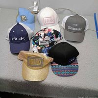 All seven branded baseball caps laid out