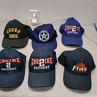 Six baseball caps arranged on surface showing front embroidery