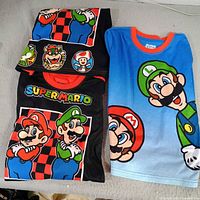 Three Super Mario pajama tops stacked showing front graphics