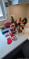 Countertop view of plush toys, mug, faux trees, packaged lights, mini stocking and hat
