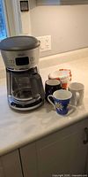 Coffee maker with mugs and filters on countertop
