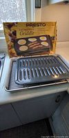 Presto Cool Touch Electric Griddle box with two metal roasting pans visible
