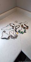 All eight assorted necklaces laid flat showing materials, colours and styles