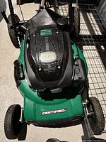Top view of Certified green push mower showing deck, wheels and handle