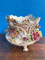 Front view of footed porcelain planter showing floral relief and openwork sides