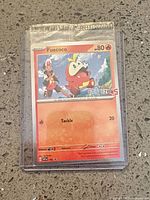 Front view of sealed Fuecoco promo Pokémon card in protective sleeve