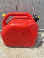 Side view of red plastic gasoline jerry can showing handle, cap and embossed capacity