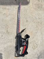 Full view of Jobmate hedge trimmer showing housing, handles, and blade with scabbard