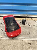 Top and side view of red Kinyo car VHS rewinder with attached power adapter cable visible